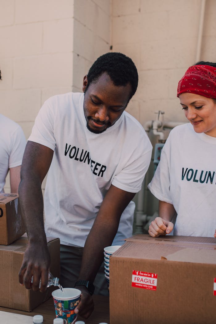 A group of volunteers working together, pouring beverages into cups outdoors.